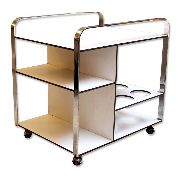 Multi-level 1960s white bar cart from France with curved chrome handles on top. Features six large holes placed on the lower level for liquor bottles. Rolls on four heavy duty casters for easy moving. This can be seen at our 5 East 16th St. location