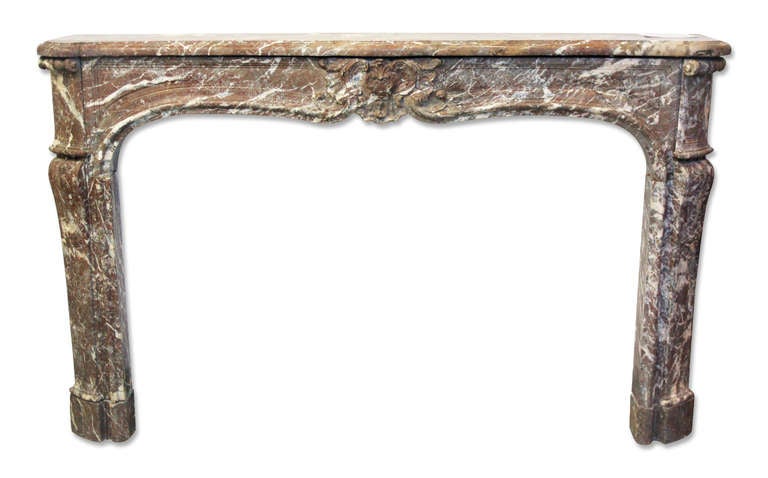 A remarkable Louis XV rouge royale marble mantel from the 18th century stands as a testament to exquisite craftsmanship. While exceptional in quality, the mantel does exhibit a minor repair on the shelf, which is nearly imperceptible thanks to the