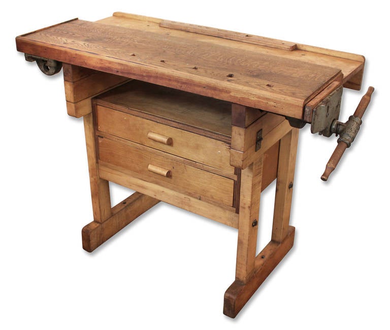 This bench features two drawers and a vise. The work bench stands on square legs having stretchers with a bottom tool tray shelf. This item can be seen at our 149 Madison Avenue location.