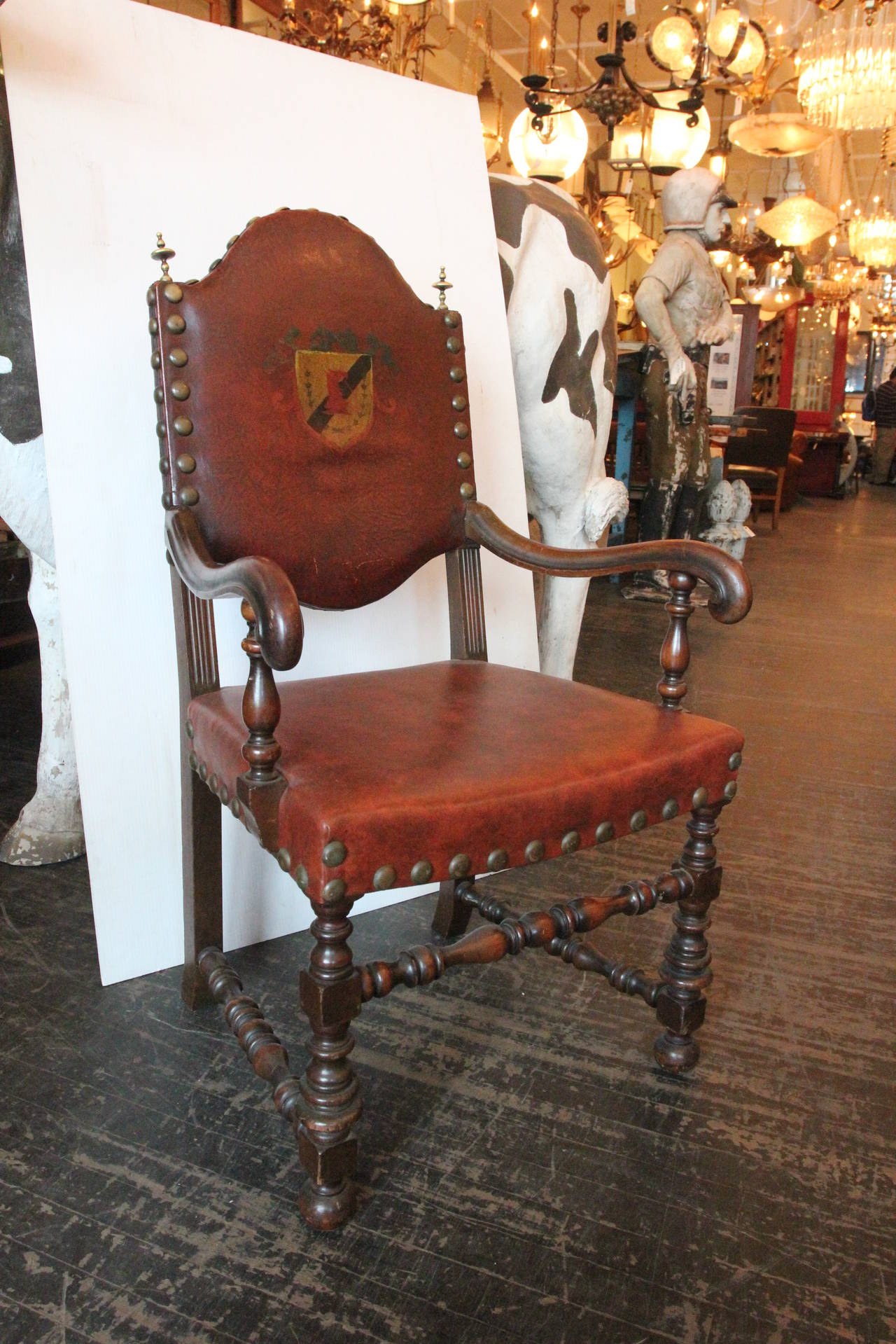 This 1920s set of six French dining chairs consists of four chairs without arms and two chairs with arms, all with brass rivets and brass finials. Reupholstered in the 1960s with dark red vinyl with a shield design on the back of the chair. These