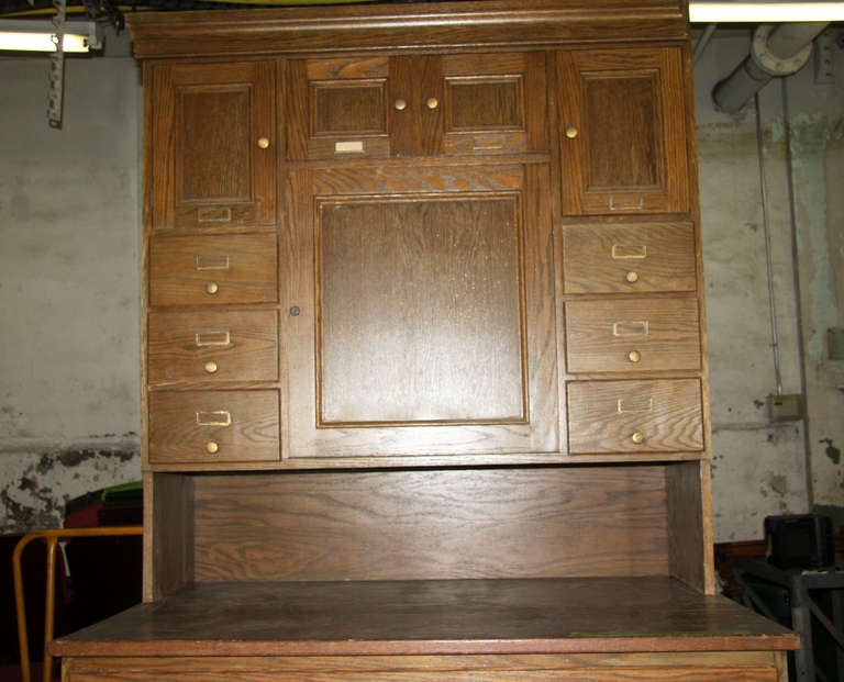 This is an early American hand built piece. It is solid American chestnut with the original brass hardware. There are seven map or vestment drawers below, six small drawers above and four cabinets above. The wood is in good condition. This item can
