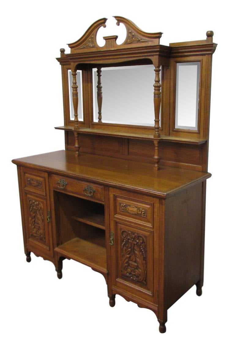This is a large intricately carved wooden server with three drawers and two cabinets with doors. It has all of its original beautifully cast brass hardware. Both cabinet doors are heavily embellished with wood carvings, while the center is two open