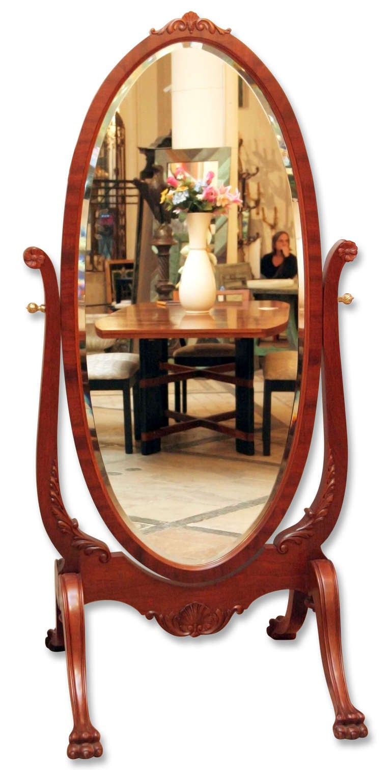 1920's swivel cheval mirror with an oval beveled mirror, claw foot legs, and beautifully hand craved detail throughout.