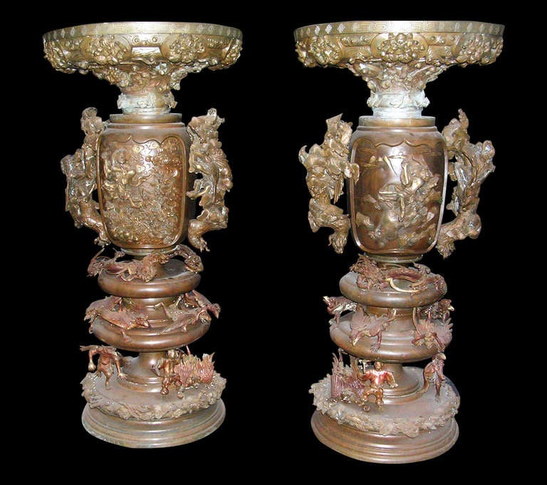 Stunning pair of 1880s Oriental bronze urns with winged figural creatures, dragons and Samurai providing a figural cover. Features a raised design throughout with two figurative dragon handles. Very heavy casting - in overall very good condition