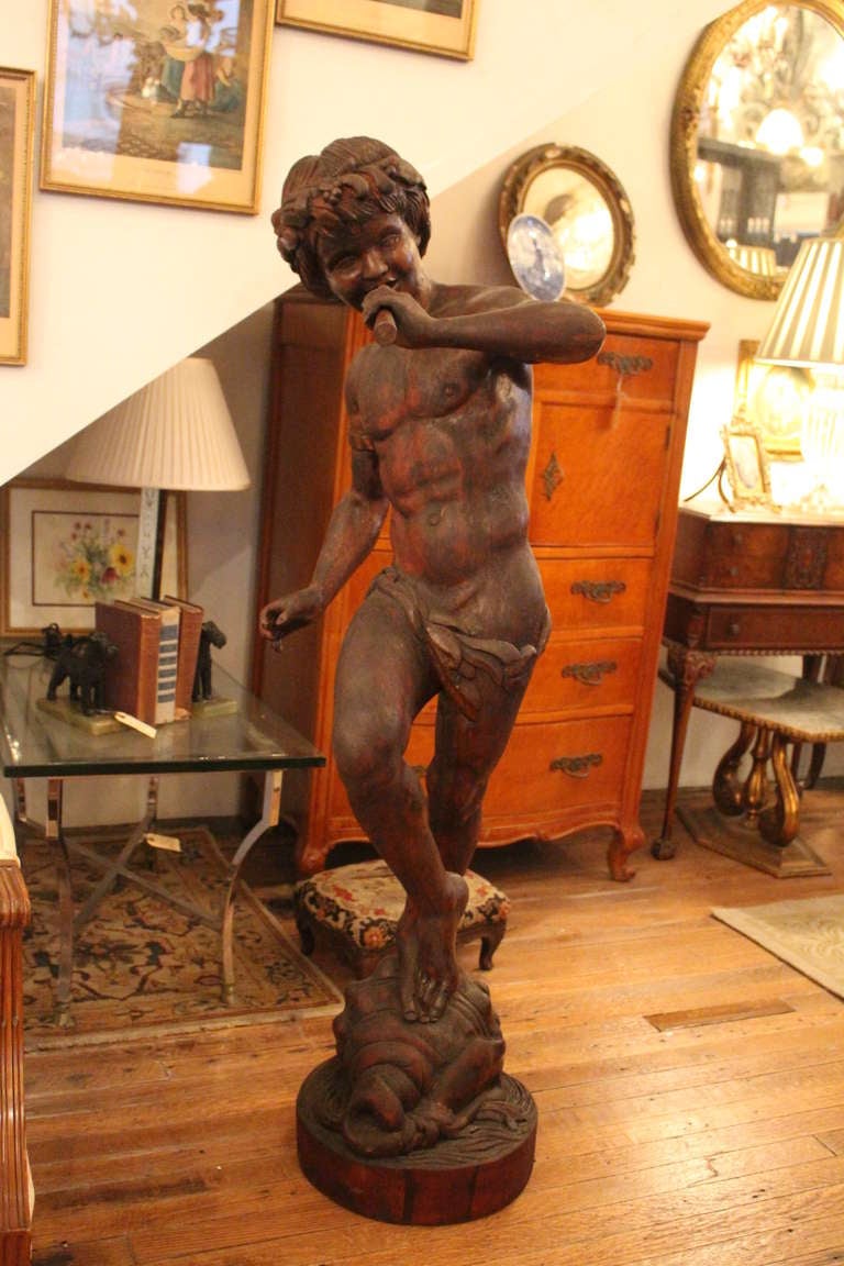 Highly detailed 1800s wooden sculpture of a Pan playing his flute while dancing on a shell. This can be seen at our 302 Bowery location in Manhattan.
