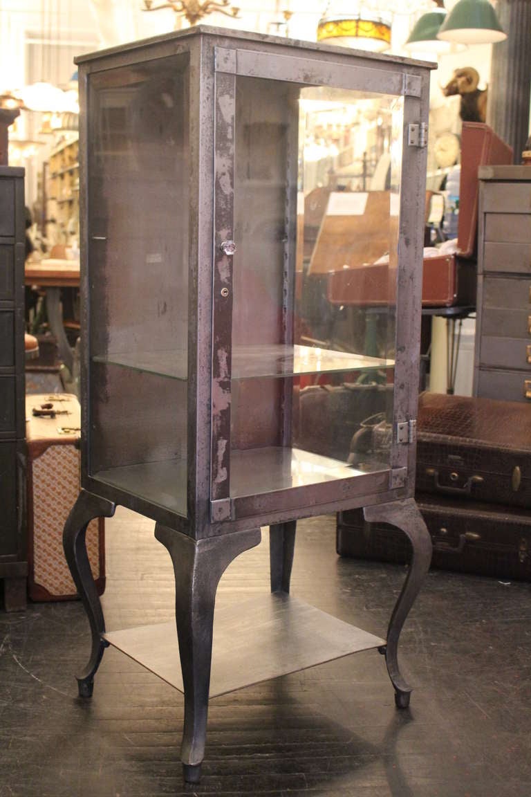 Handsome striped medical cabinet dating back to the 1920's. Three sided glass piece with three glass shelves and cabriole legs. This can be seen at our 302 Bowery location in Manhattan.