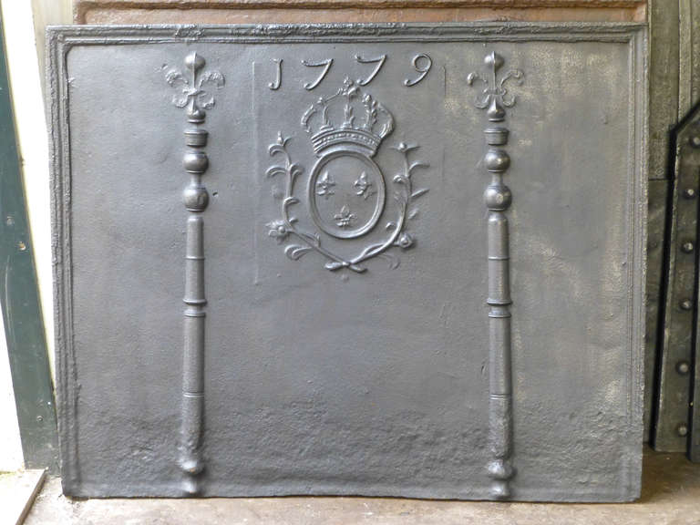 Plaque de cheminée du XVIIIe siècle avec armoiries de France, piliers et date de fabrication 1779. Les fleurs de lys et la couronne ont été partiellement tronquées pendant la Révolution française. La plaque de cheminée est de style Louis XV et date