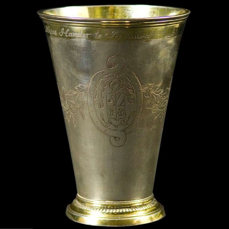 An Estonian silver gilt beaker, the body decorated with floral decoration and cartouché, two engraved with figural scenes and one with original Coat of Arms. The rim engraved with an inscription - 