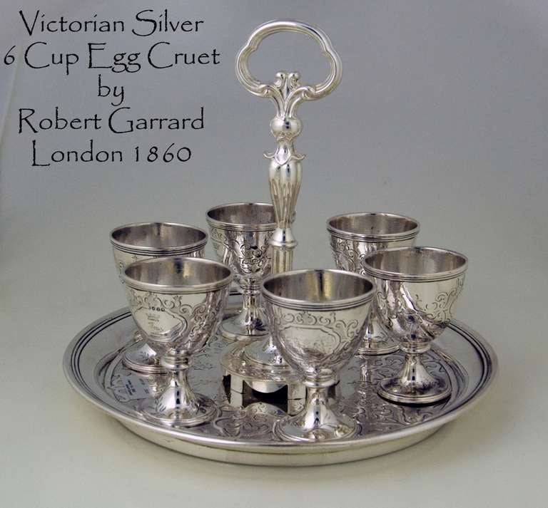A mid Victorian silver circular egg cruet fitted with six egg cups each engraved with a harbour/sea scape scene and crested on the opposite panel. 

Signed/Inscribed/Dated: London 1860 by Robert Garrard

ROBERT GARRARD II, LONDON (1818-1881)