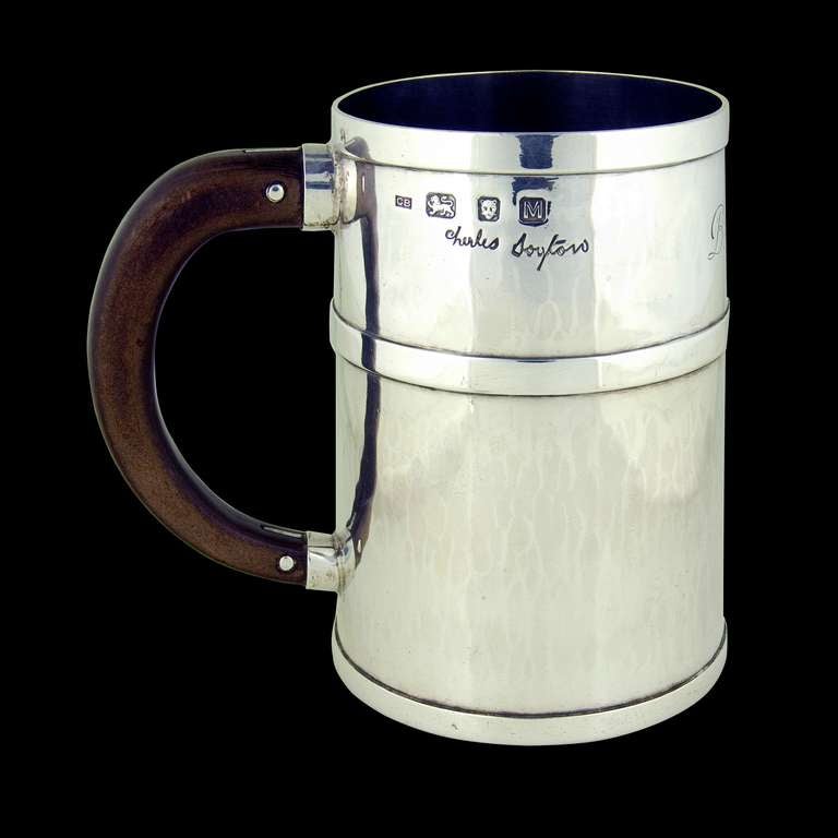 A wooden handled hand beaten silver mug inscribed 'BROCKELBANK' and having makers signature. 

Signed/Inscribed/Dated: London 1947 by Charles Boyton