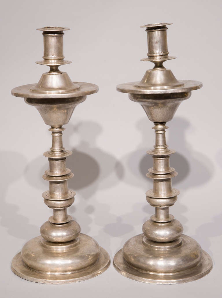 Cette paire de chandeliers en argent péruvien illustre les détails élégants caractéristiques des pratiques d'orfèvrerie de l'époque coloniale espagnole. Les chandeliers se caractérisent par une base circulaire légèrement bombée et des tiges