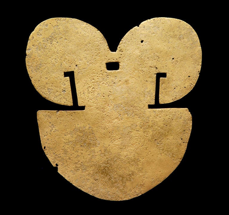 This pre-Columbian pectoral (or breast plate) from the Quimbaya Culture of Columbia represents, in a very stylized form, a human face and head; the top two curved finials stand in for a traditional headdress worn by men of the ancient Quimbaya