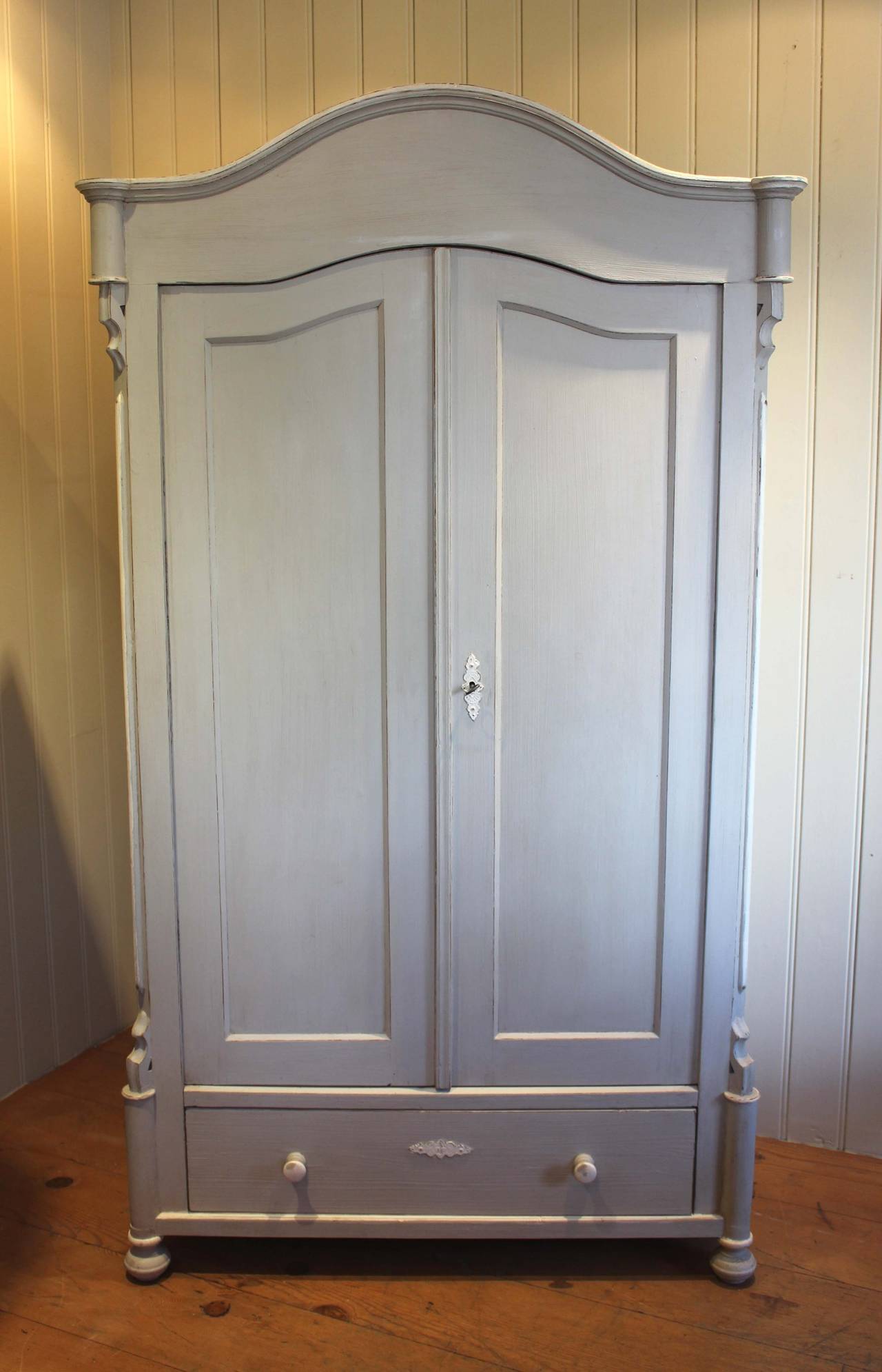 Pale blue painted continental cupboard having two doors with an arched top with cotton reel turnings and raised beading with a drawer to the base . Internally it has a hanging rail. 
(East European, c. 1890)