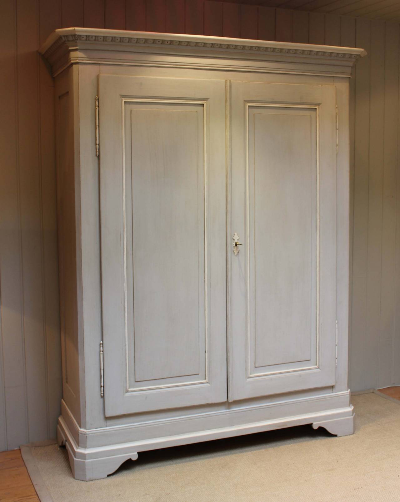 Late 19th century painted continental wardrobe having panelled doors with a carved top decoration fitted with an internal hanging rail. The internal depth is 43cm. This wardrobe fully dismantles