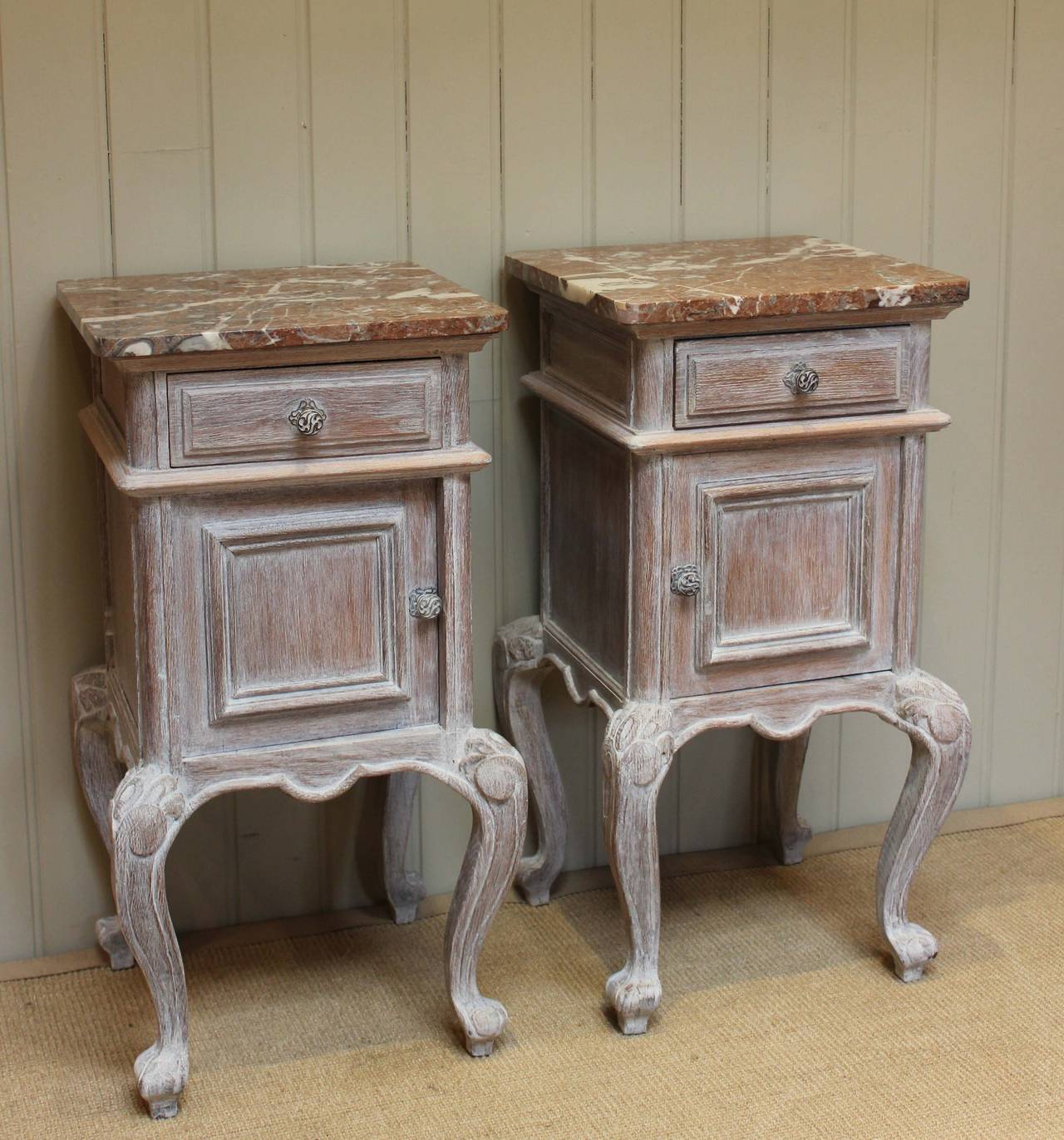 Pair of French limed oak marble top bedside cabinets having a single drawer above a cupboard base raised on cabriole legs