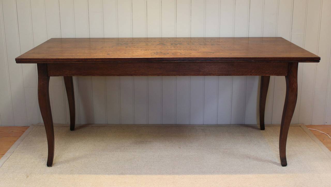 French solid oak foyer table having vintage French lettering to the top raised on shaped legs. The height from the floor to the undertier is 61 cm