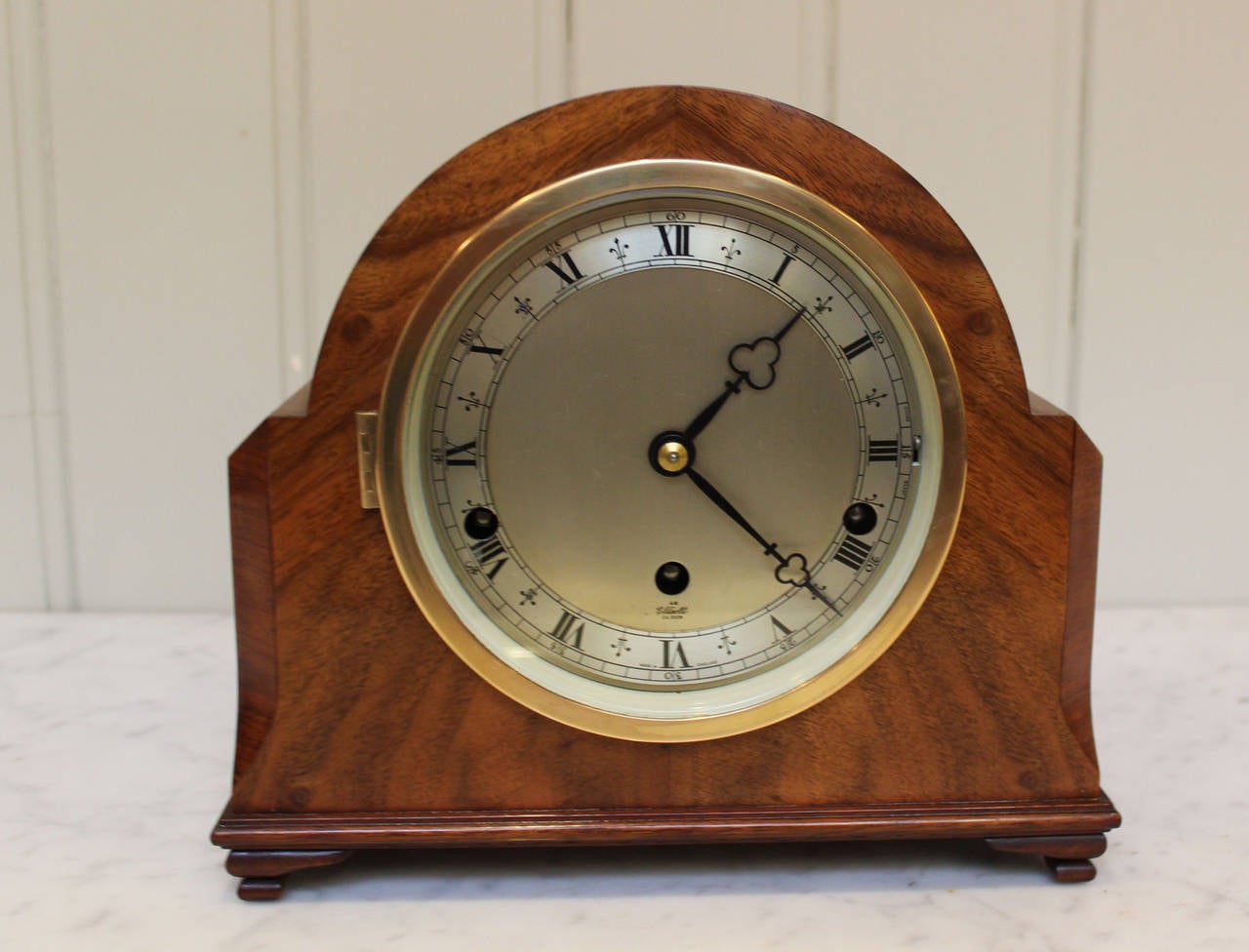 A walnut cased dome top mantel clock having Westminster (big Ben ) chimes. It as a figured walnut veneered case,with small bracket feet. The bras bezel has a bevel edge glass with a silvered chapter ring. It has a strike silent switch and is signed