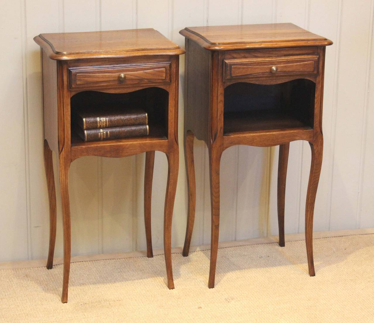 Pair of French oak bedside cabinets having a single drawer above an open cupboard base raised on cabriole legs
