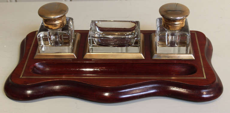 A mahogany inkstand, with two inkwells and a central tray for desk accessories.