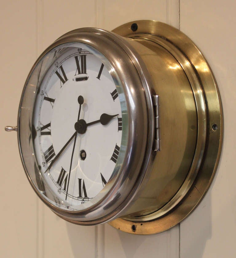 A very heavy ships clock, having a solid brass case, with a polished nickel bezel, which has a thick bevel edge glass. The white vitreous enamel dial has Roman numerals and a sweep seconds hand. It has an 8 day lever platform movement.
This
