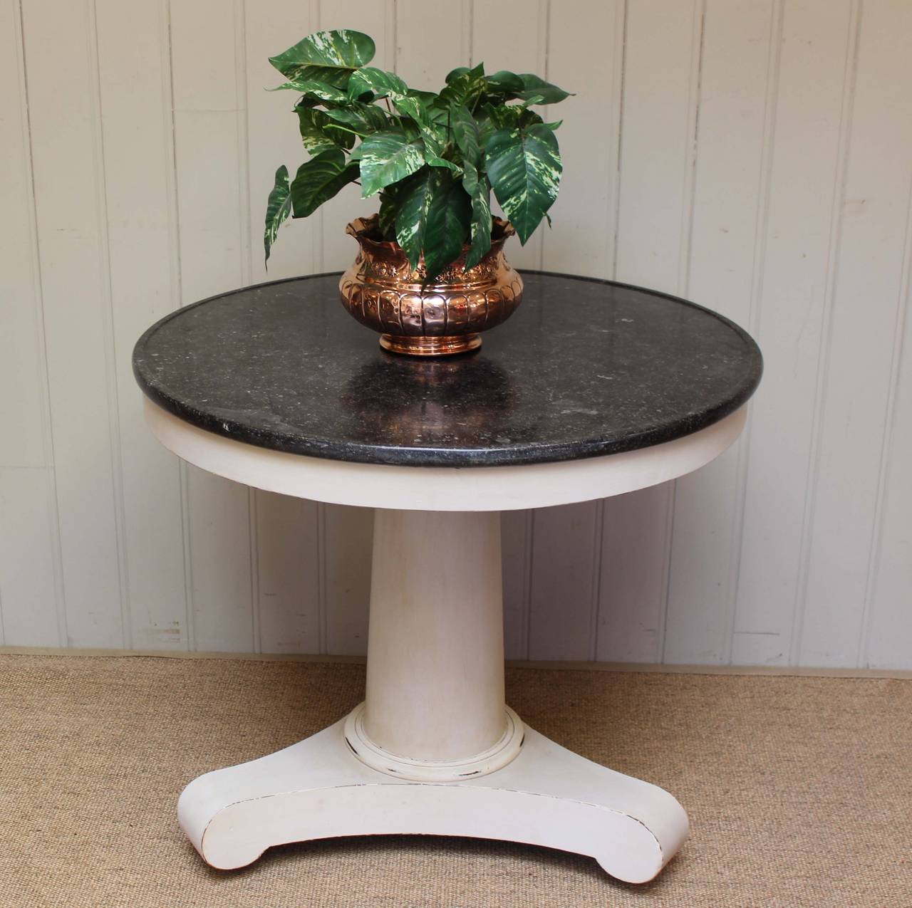 Painted central table having a substantial pedestal painted base with a polished granite top.