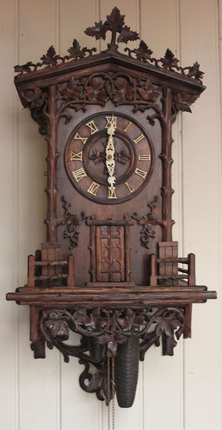 A very rare large wall hanging Black Forest trumpeter clock. It has a fruitwood case with traditional applied carved vine leaves incorporating an integral bottom bracket. It has original finely carved bone hands and applied numerals. On the hour the