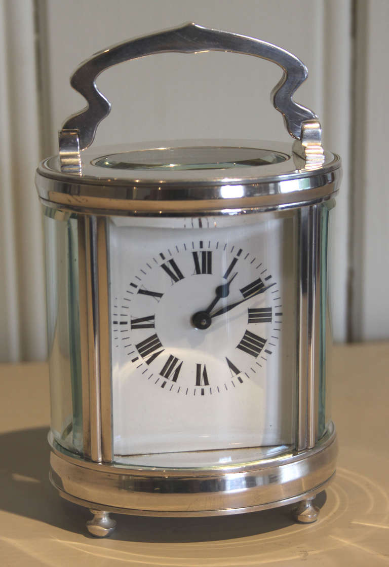 A French timepiece carriage clock dating to the beginning of the 20th Century. It has an oval case surrounded by four bow glasses with bevel edges. The 8 day movement has a lever platform. It comes complete with its silver plated double ended