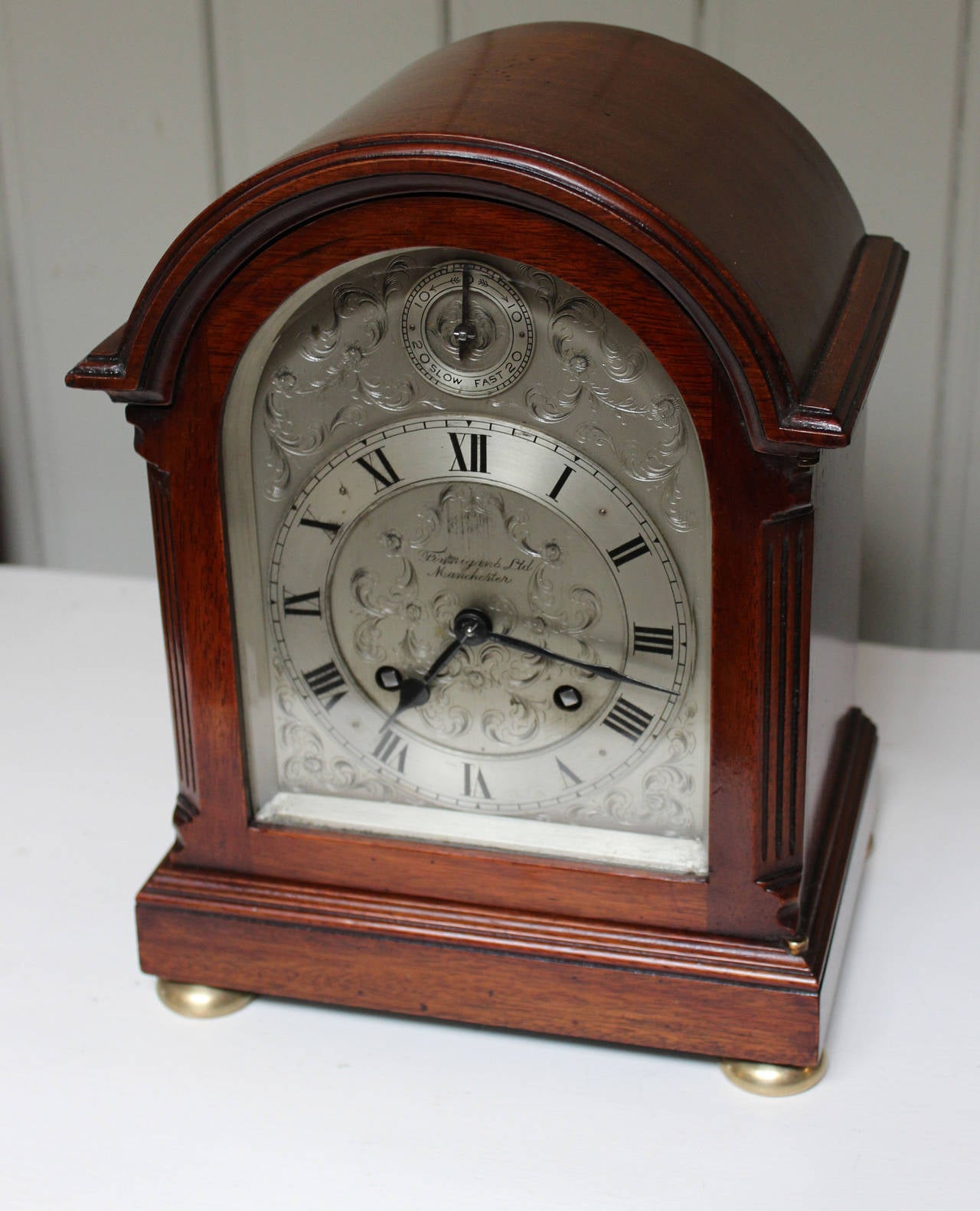 A good quality and nicely proportioned English bracket/mantel clock. The mahogany case has a break arch top with reeded canted sides and brass bun feet. It has a well hand engraved and silvered dial, has a regulation rise and fall dial and is signed