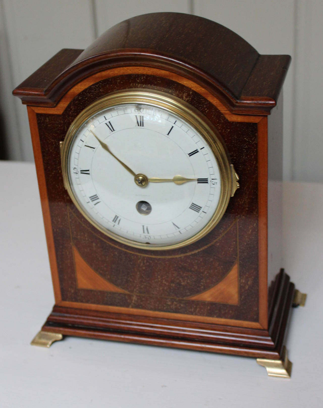 A very original and well proportioned mahogany mantel clock, dating to the early 1900s. It has a solid mahogany case, inlaid with satinwood quadrants and boxwood stringing. It has a convex bevel edge glass and a convex enamel dial. The French