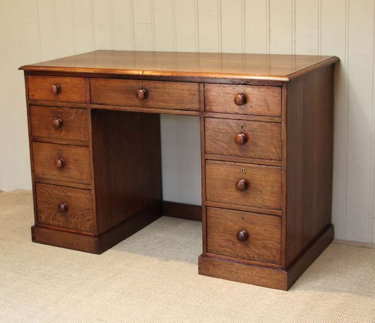Oak pedestal desk having a long top drawerover a kneehole base above six drawers