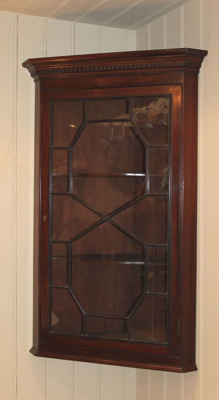 Edwardian mahogany corner wall cabinet having an astragal glazed door with shaped internal shelves.