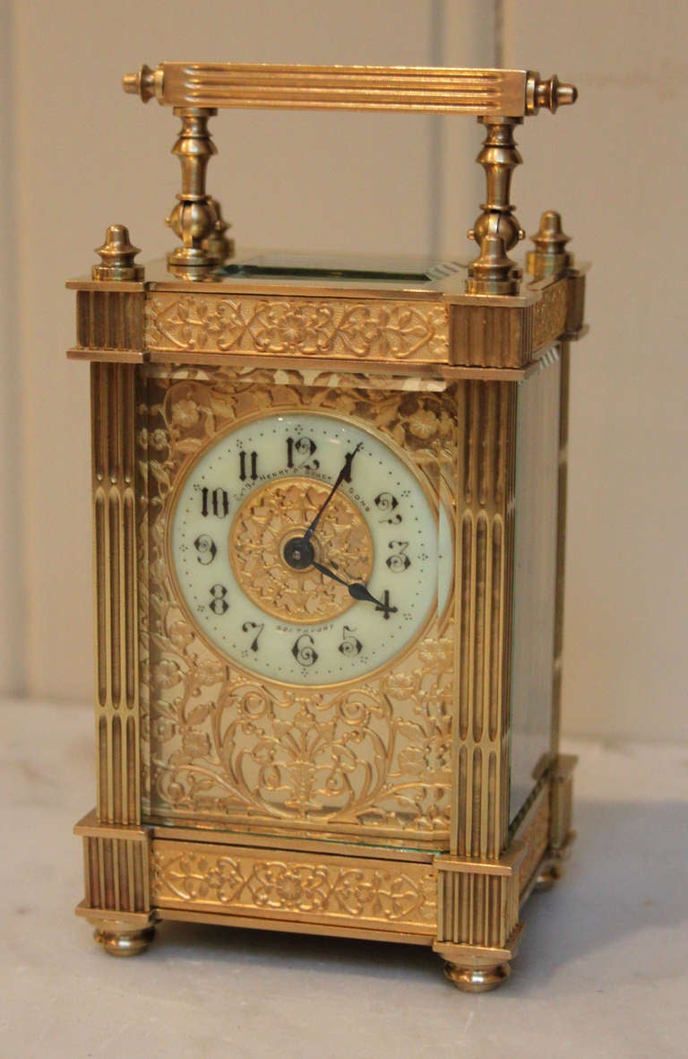 An ornate carriage clock, having a brass case, with reeded columns, top and base embossed gilt banded panels and corner finials. The dial has a pierced gilt dial mask, with enamel chapter ring. The 8 day movement has a cylinder platform. The dial is