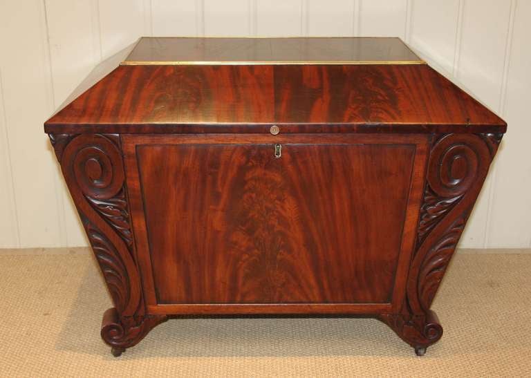 William IV mahogany sarcophagus shaped cellarette having scroll edges and a brass banded figure mahogany top