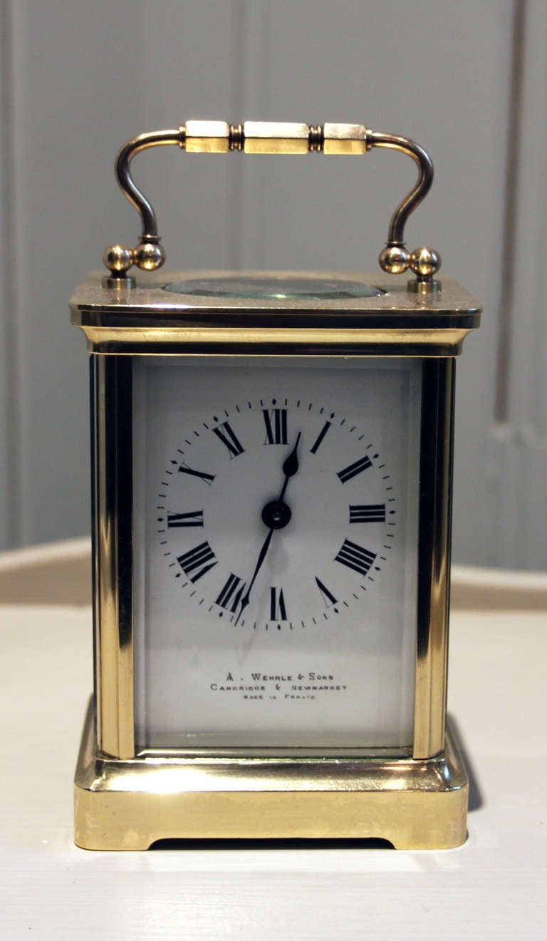 A French Timepiece carriage clock, , having a brass corniche case with an oval top window. It has bevel edge glass, and an enamel dial signed by the original retailers, A Werhrle & Sons, Cambridge & Newmarket. It has an 8 day movement with a lever