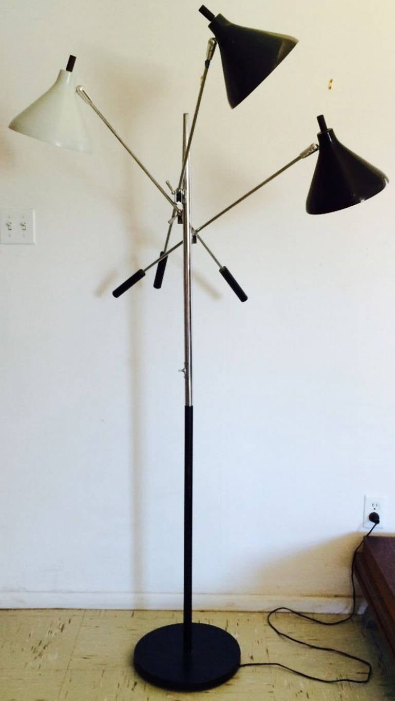 A fine Mid-Century triennale floor lamp. Standing metal item features three adjusting poles with enamel painted shades (black and gray). Chrome plated stem and black enamel base retains original wiring and switches (untested). Item intact in