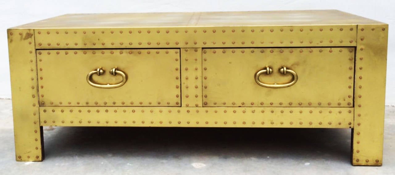 A fine Sarreid brass-clad low chest table. Brass-clad wood chest features double drawers, brass stud trim and pulls (front and sides). Original pristine finish intact.