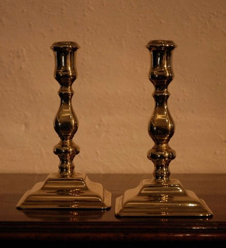 A pair of Queen Anne period brass candlesticks