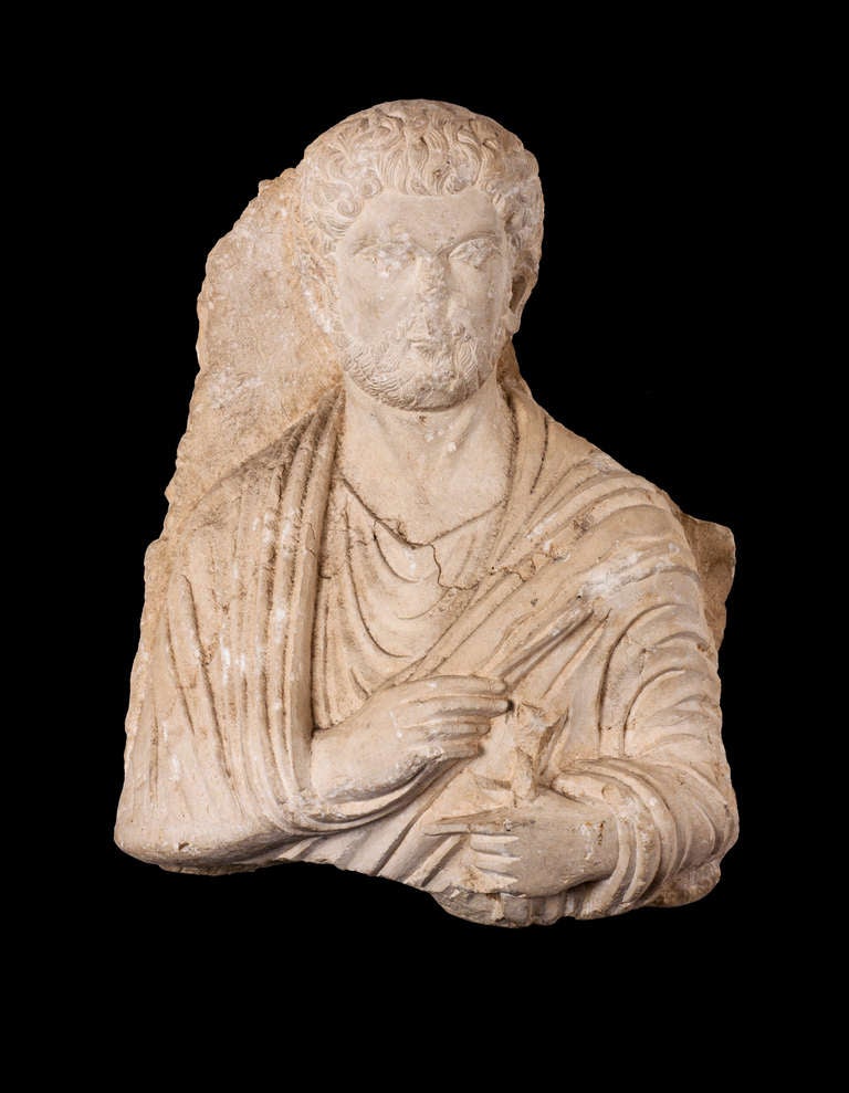 A bearded male figure dressed in a robe is carved on the relief, with a volumen (book) in his  left hand, while the right hand holds a fold of his robe. There are some gaps on his face around the eyes, nose and chin, which, given the precise