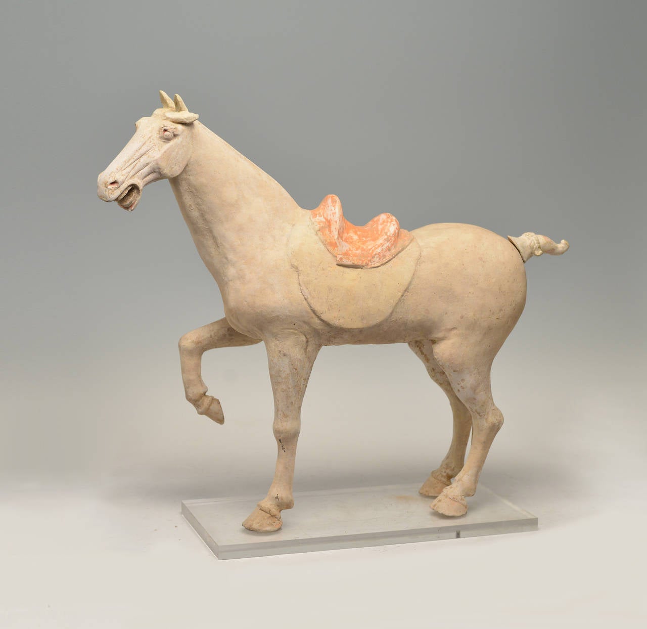 Figure en poterie peinte représentant un cheval cabré, la jambe droite levée et la tête tournée vers la gauche, la tête bien modelée avec des traits nets sous les oreilles dressées, la selle peinte d'un motif cruciforme, VIIIe siècle.