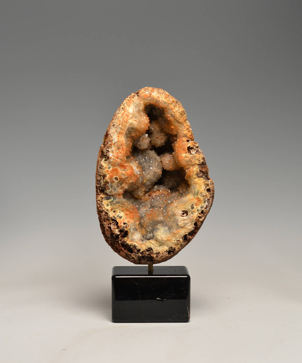 Agate stone geode specimen with dark brown rock crystal base.