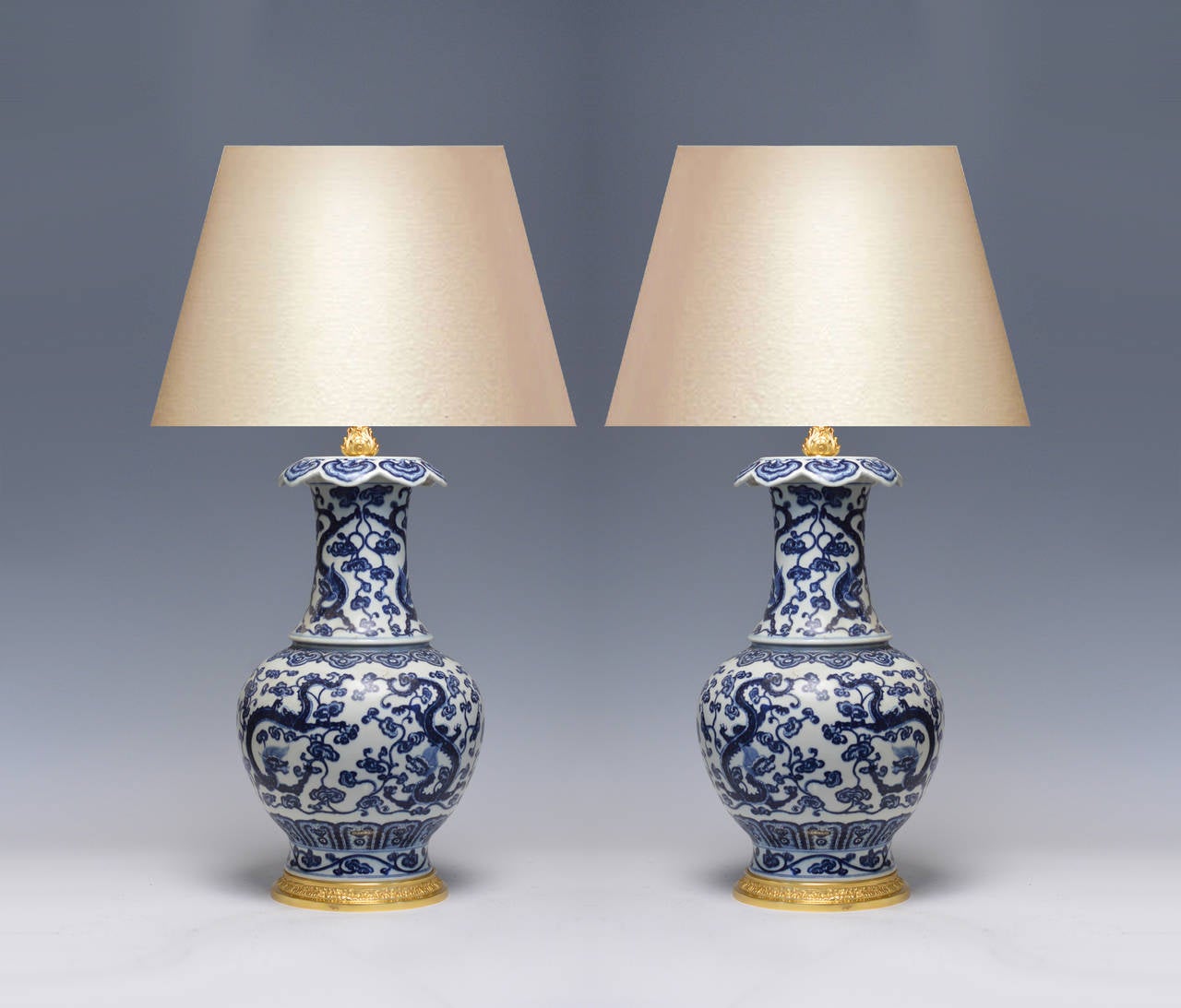 Pair of fine painted blue and white porcelain lamps with dragon and floral scroll decoration, gilt brass bases. Measure: 18