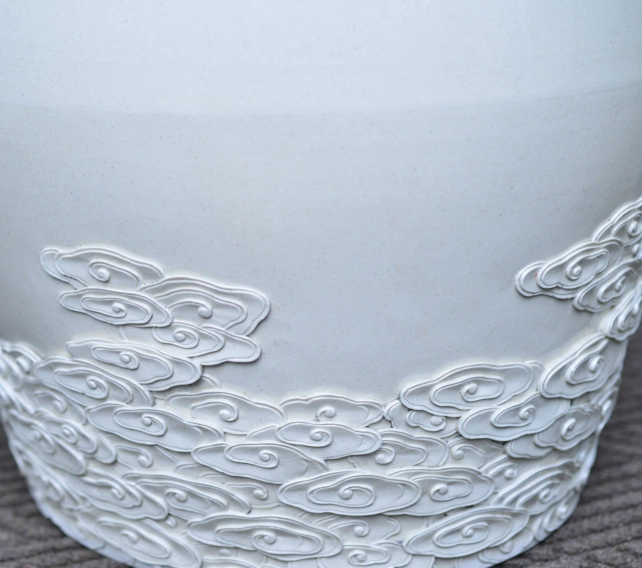 Pair of off-white porcelain stools with finely carved cloud decoration at the lower composition.
