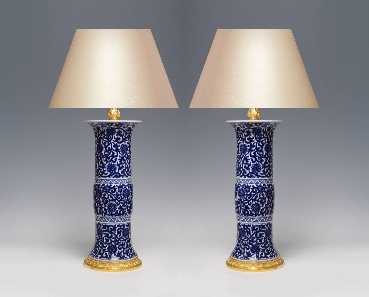 Pair of fine painted beaker form blue and white porcelain lamps with floral scroll decoration, gilt brass bases. 17.5