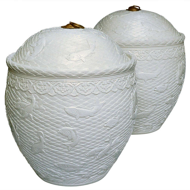 Une paire de pots en porcelaine blanche tendre finement sculptée avec couvercles, poissons nageant dans les décorations de vagues élégantes.