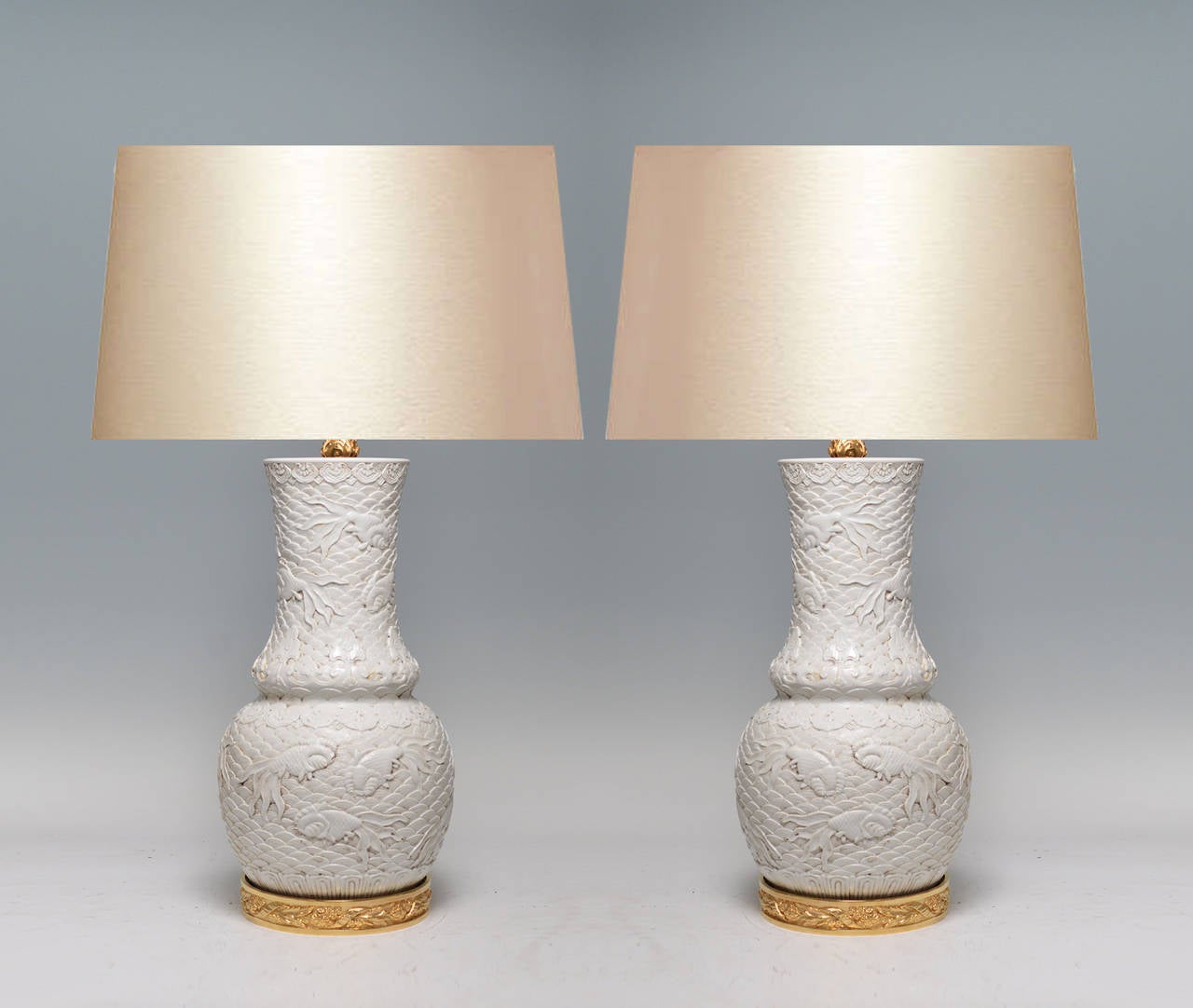 Fine carved white porcelain lamps with golden fish swimming in the stylish wave decorations gilt bronze bases.