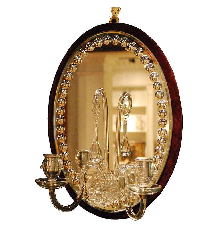 A pair of oval burgundy velvet-backed two-light mirrored sconces with blown glass arms centering a tear-drop pendant.