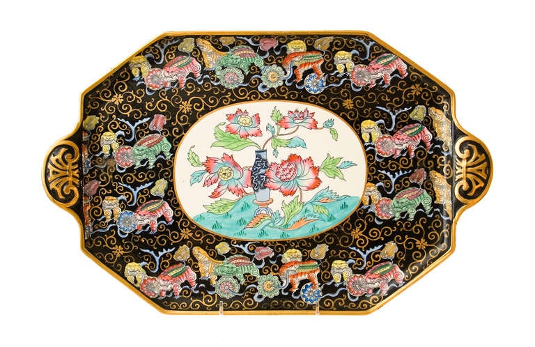 A 10 piece Ashworth porcelain cabaret set with polychrome decoration of foo dogs & gilt brocade on black ground. A Teapot and cover, sugar bowl and cover, creamer, two tea cups and saucers, tray. Hairline crack to one cup.
