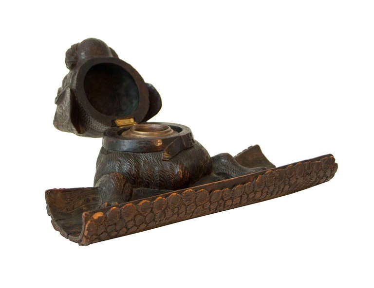 A charming English Victorian large carved wood inkwell modeled as a dog with glass eyes, his paws resting on a hollow log penrack.