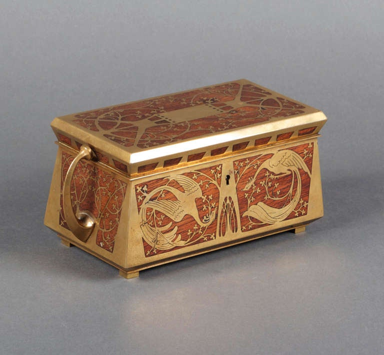 A rosewood casket inlaid extensively in brass with a design of stylized trees to the lid, back and sides, and with a design of stylized phoenixes to the front. The interior lined with red velvet and with faceted brass handles to either side.

The