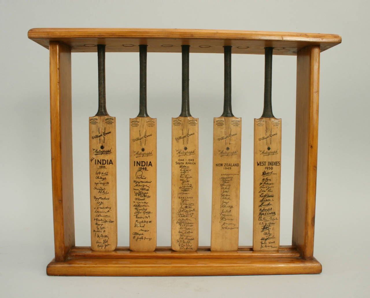 Gunn and Moore miniature cricket bat display. 
A set of five miniature Gunn and Moore Cricket bats in a polished pine display stand. The bats are ‘William Gunn “the AUTOGRAPH” bats all with facsimile signatures on the front and Gunn & Moore
